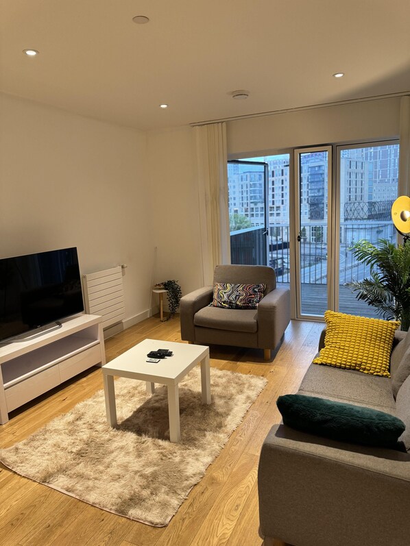 A modern living room with a flat-screen TV, a sofa, a chair, and a coffee table.