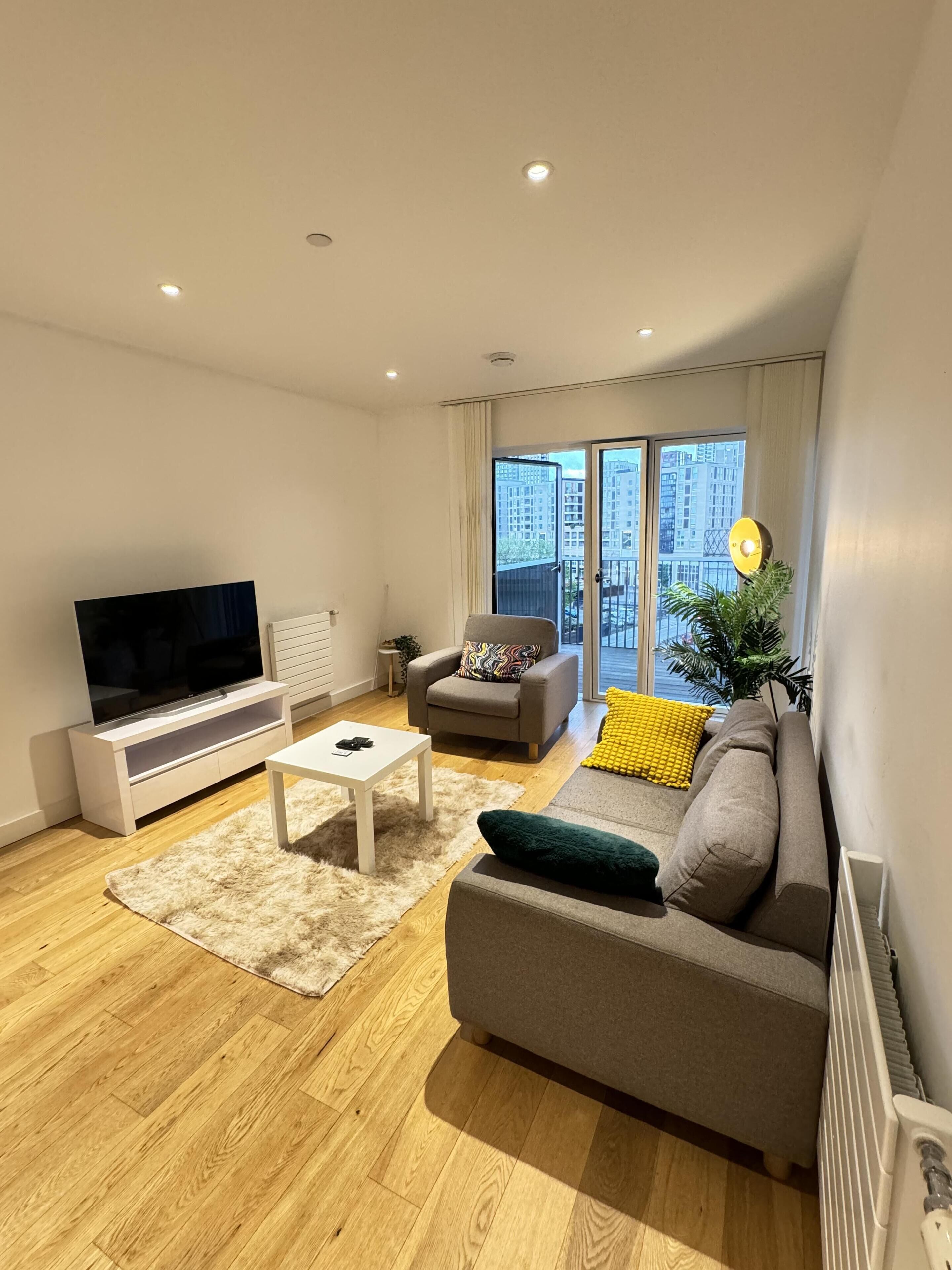A modern living room with a flat-screen TV, a sofa, a chair, and a coffee table.