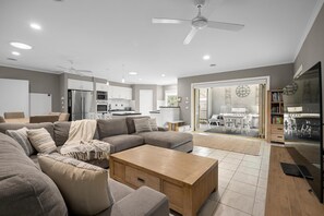 Relax in a spacious living area with a large sofa, coffee table, and dining space leading to a balcony with outdoor views.