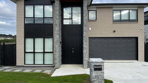 Ein modernes, zweistöckiges Haus mit Garage, Steinverkleidung und großen Fenstern.