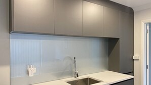 Eine moderne Küche mit grauen Schränken, einer weißen Arbeitsplatte und einem Edelstahlspülbecken.