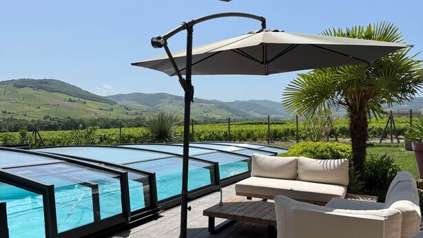 A poolside area with lounge chairs, a table, and a large umbrella.