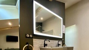 A modern bathroom with a large mirror, two sinks, and a wooden vanity.