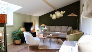 A modern living room with a high ceiling, a sofa, a coffee table, and a television.