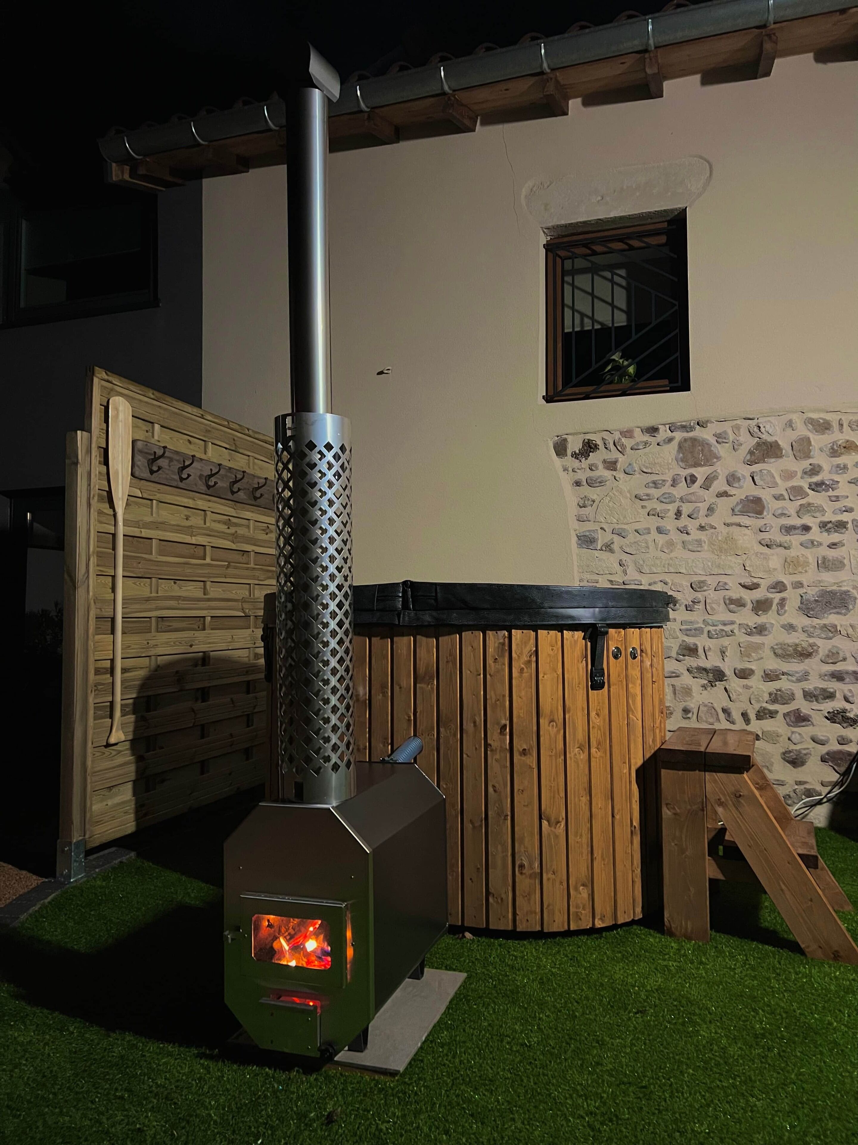Een houtkachel, een houten jacuzzi en een stenen muur.