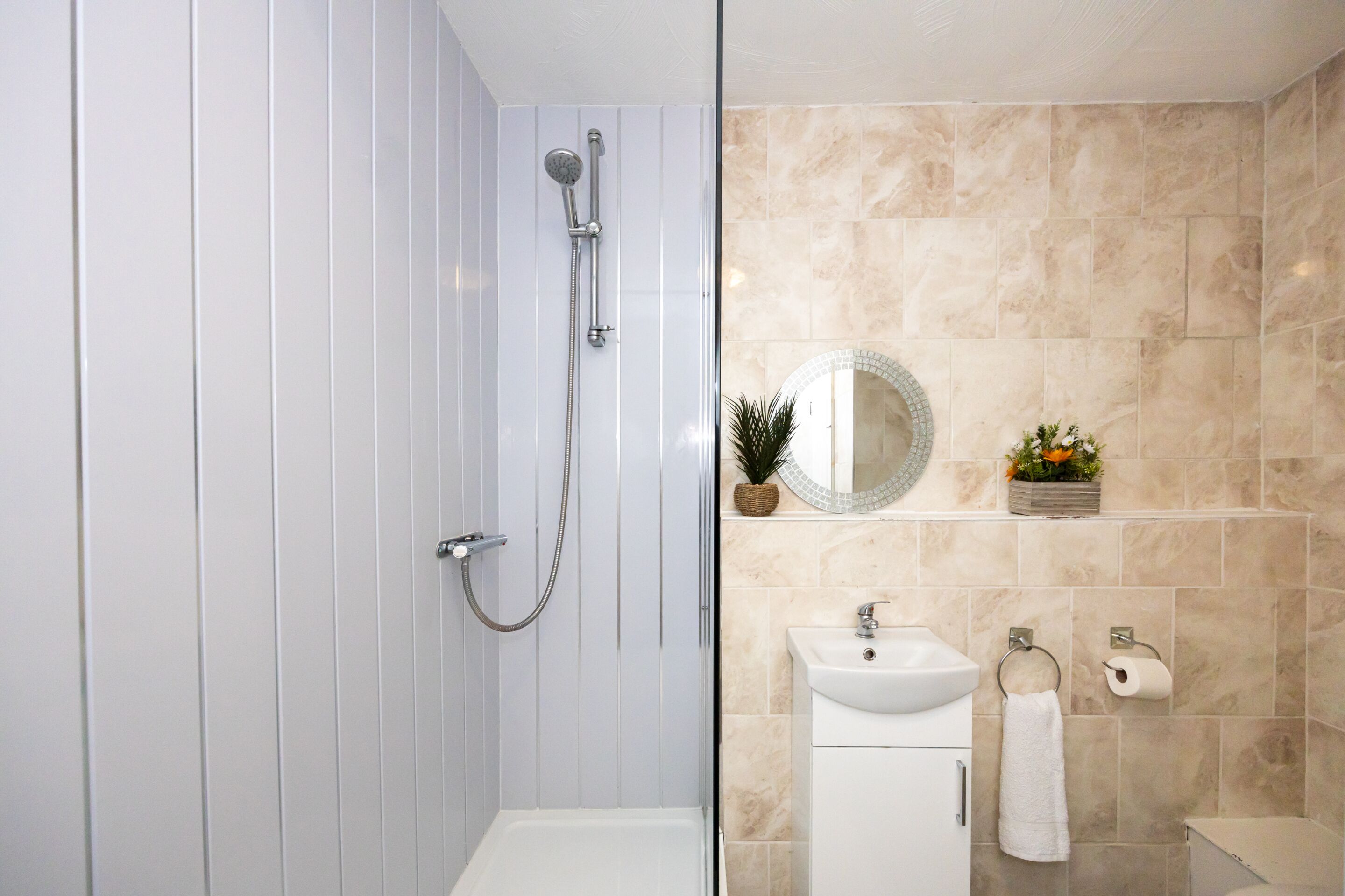 Een moderne badkamer met een inloopdouche, wastafel en spiegel.