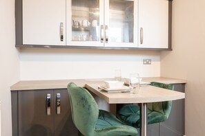 Una cocina moderna con un armario empotrado, encimera de madera y una silla tapizada en verde.