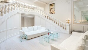 A spacious living area with a white staircase, a white sofa, and a glass coffee table. - The Great Beauty – Pantheon Luxury Stay (Roma)