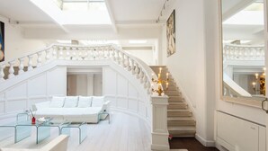 A spacious living area with a white staircase, a glass coffee table, and a white sofa. - The Great Beauty – Pantheon Luxury Stay (Roma)