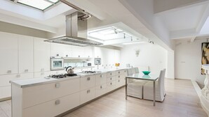 A modern kitchen with a central island, skylights, and a dining area with a table and chairs. - The Great Beauty – Pantheon Luxury Stay (Roma)