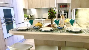 Una cucina moderna con isola centrale, sgabelli da bar e zona pranzo apparecchiata per un pasto.