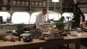 Uno chef al lavoro in una cucina luminosa, con diversi utensili da cucina e ingredienti sul bancone.