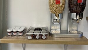 A self-serve station with two large dispensers for granola and nuts, and a tray of Nutella jars. - Le Clos du Thoronet (Le Thoronet)