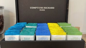 A black box with compartments containing various tea packages labeled with names like "THÉ VERT BIO ORGANIC GREEN TEA" and "THÉ NOIR AROMATISÉ FLAVOURED BLACK TEA". - Le Clos du Thoronet (Le Thoronet)