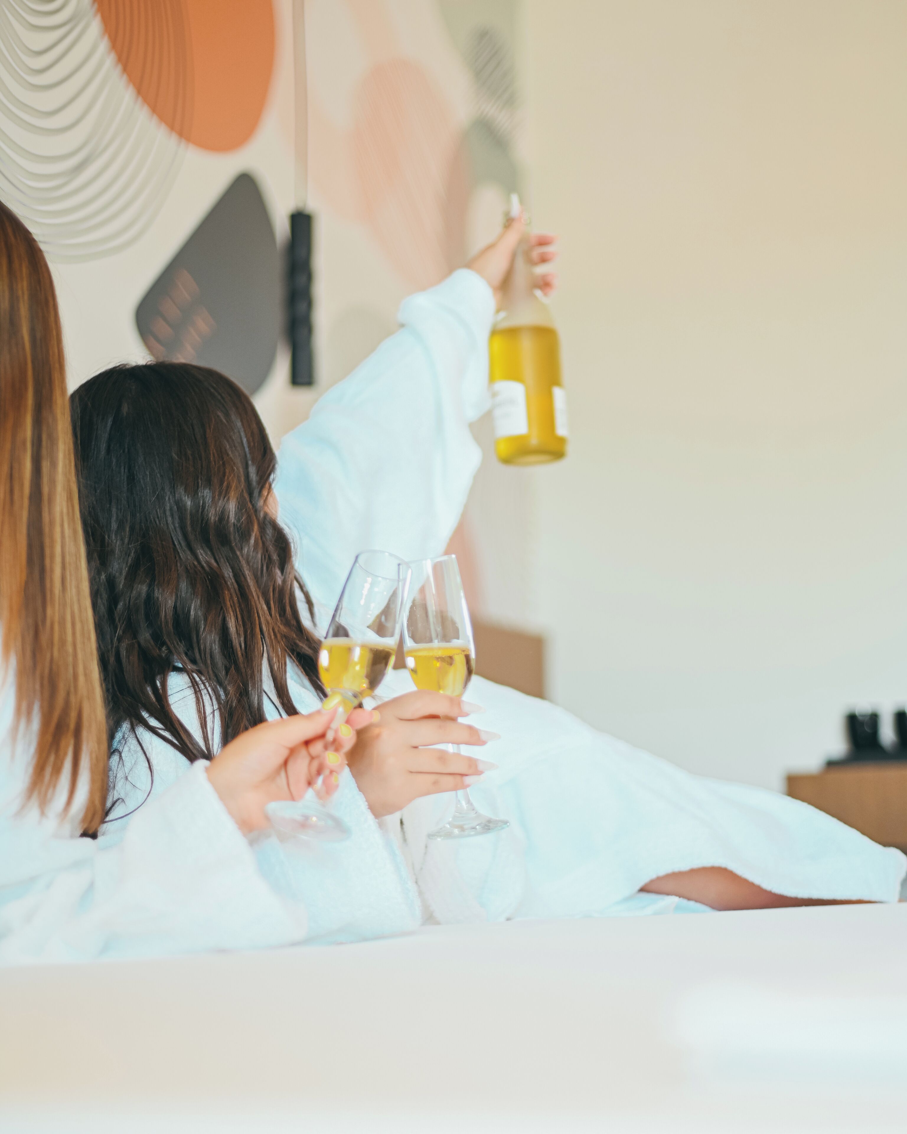 A person holding a wine bottle and two glasses of wine.