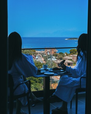 Two people seated at a table with a view of the sea and a distant island. - Monun Hotel (Ksamil)
