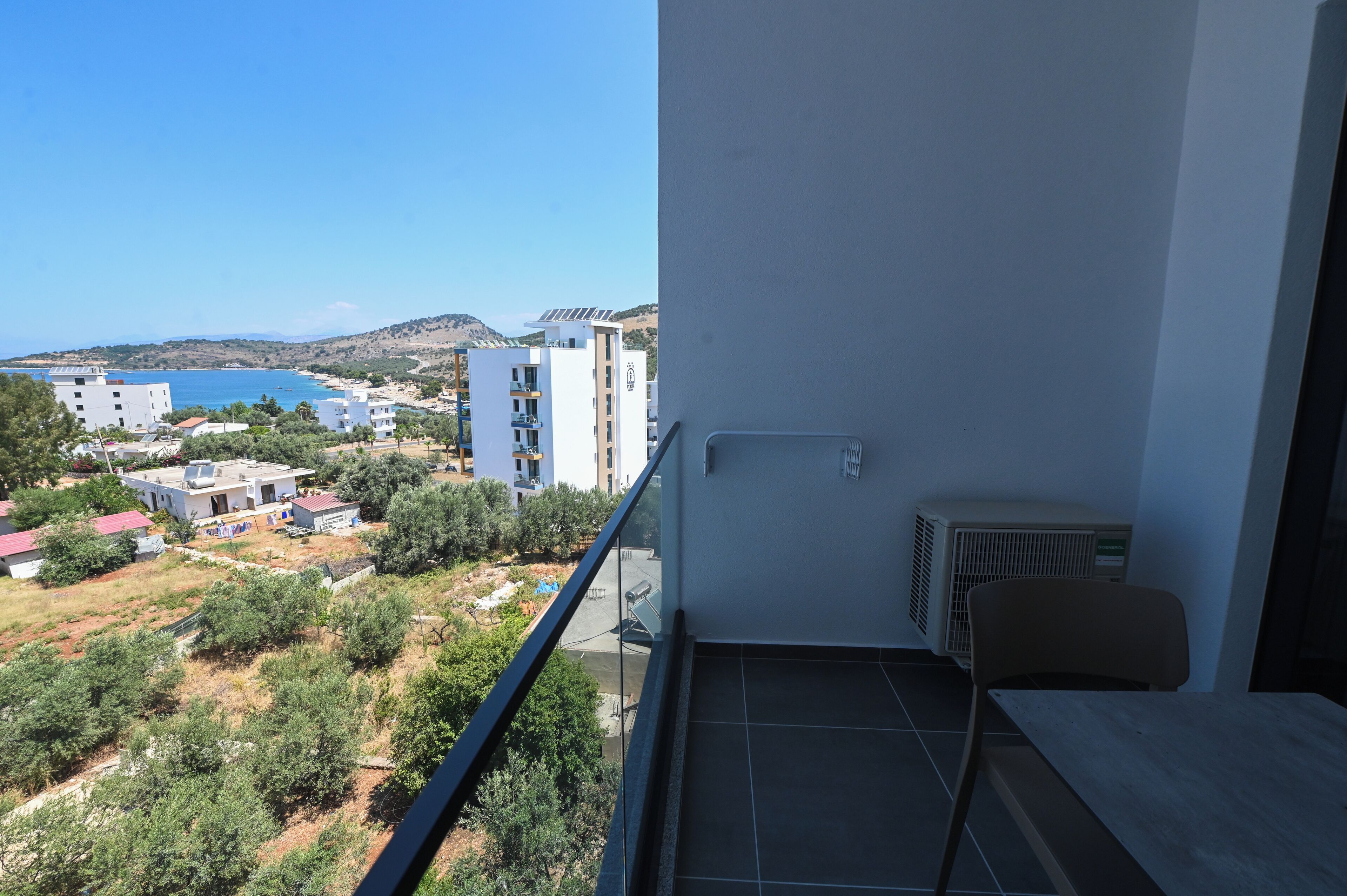 A balcony with a view of a coastal area, including buildings and a body of water.