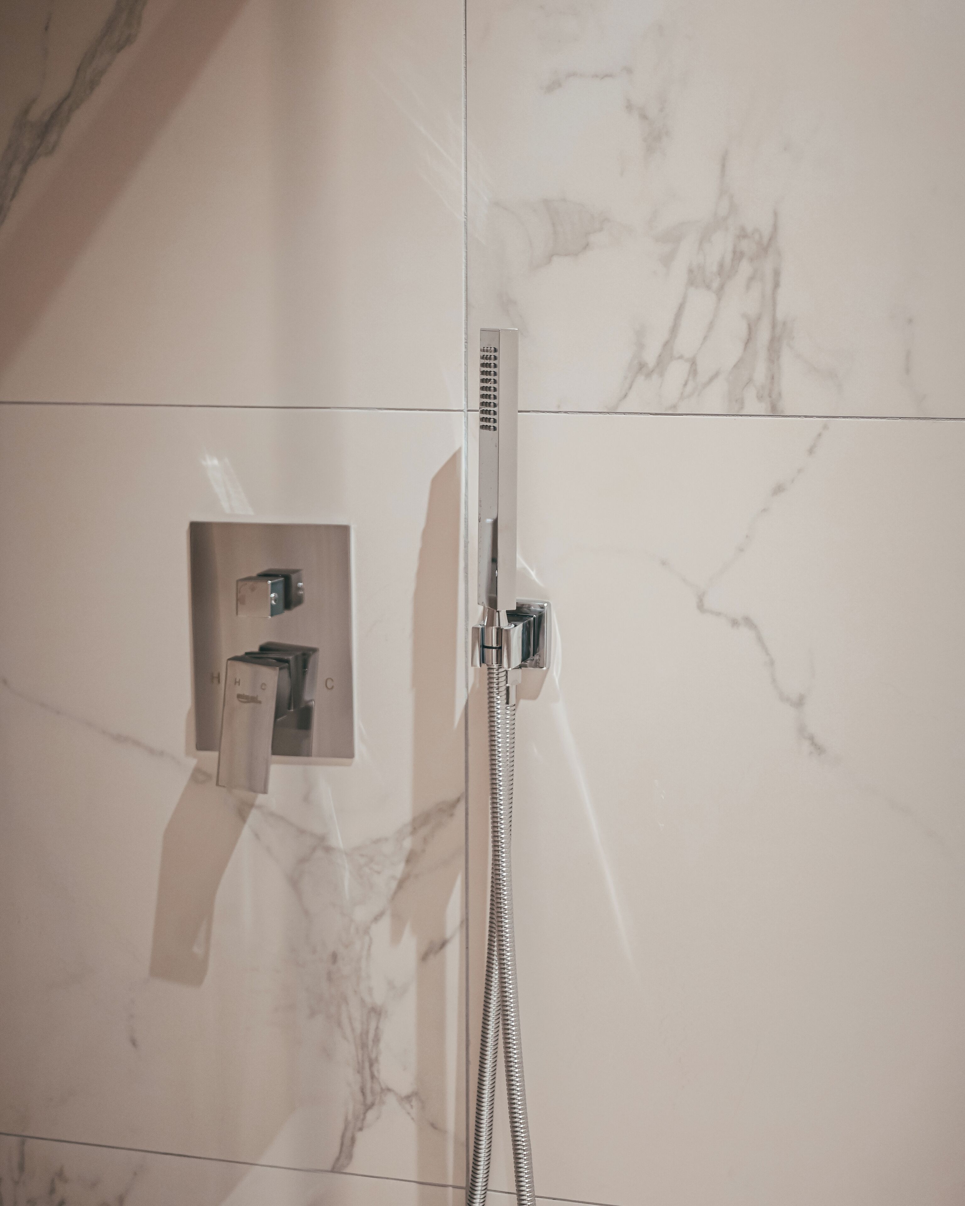Une salle de bain équipée d’une douche, d’un porte-serviettes et d’un panneau de commande.