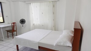 Een keurig opgemaakt slaapkamer met een bed, een bureau en een stoel.