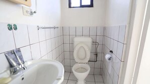 Een compacte, schone badkamer met een wit toilet, een wastafel en een raam.