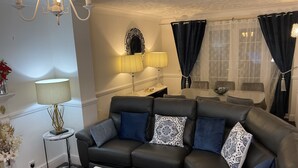 A modern living room with a black leather sofa, a white coffee table, and a small side table with a lamp. - Stunning 4-bed House in Rochester (Rochester)