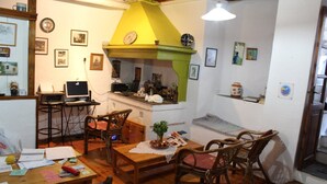 Un salon chaleureux avec un plancher en bois, une cheminée verte et un coin repas comprenant une table et des chaises.