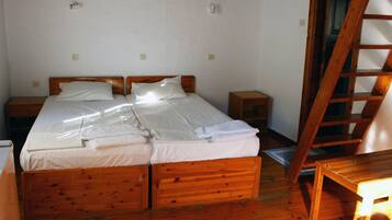 Quarto com duas camas de madeira, uma escada de madeira e uma pequena mesa de madeira.