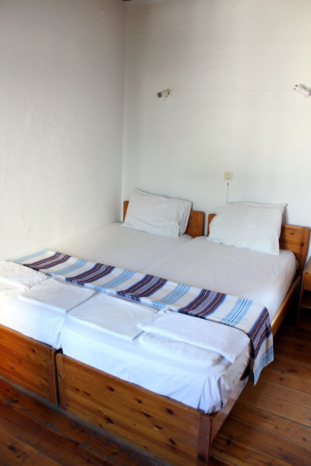 A single wooden bed with white bedding and striped blankets.