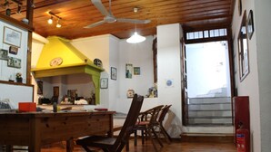 Une cuisine chaleureuse avec un plancher en bois, un coin repas avec des chaises, un ventilateur de plafond et un escalier menant à l’étage supérieur.