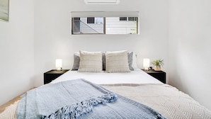 A bedroom with a bed, two bedside tables, a window with a view of a staircase, and an air conditioning unit. - Comino on Connemara - Lagoon Style Pool (Trinity Beach)