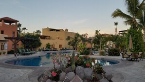 Ein Poolbereich eines Resorts mit Liegestühlen und einem Gebäude im Hintergrund.