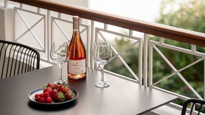 Una mesa con una botella de vino, dos copas y un plato de fresas en un balcón.