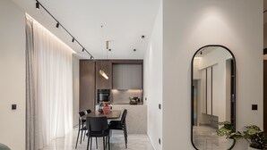 Una cocina moderna con comedor, que cuenta con piso de mármol, muebles contemporáneos y un espejo grande.