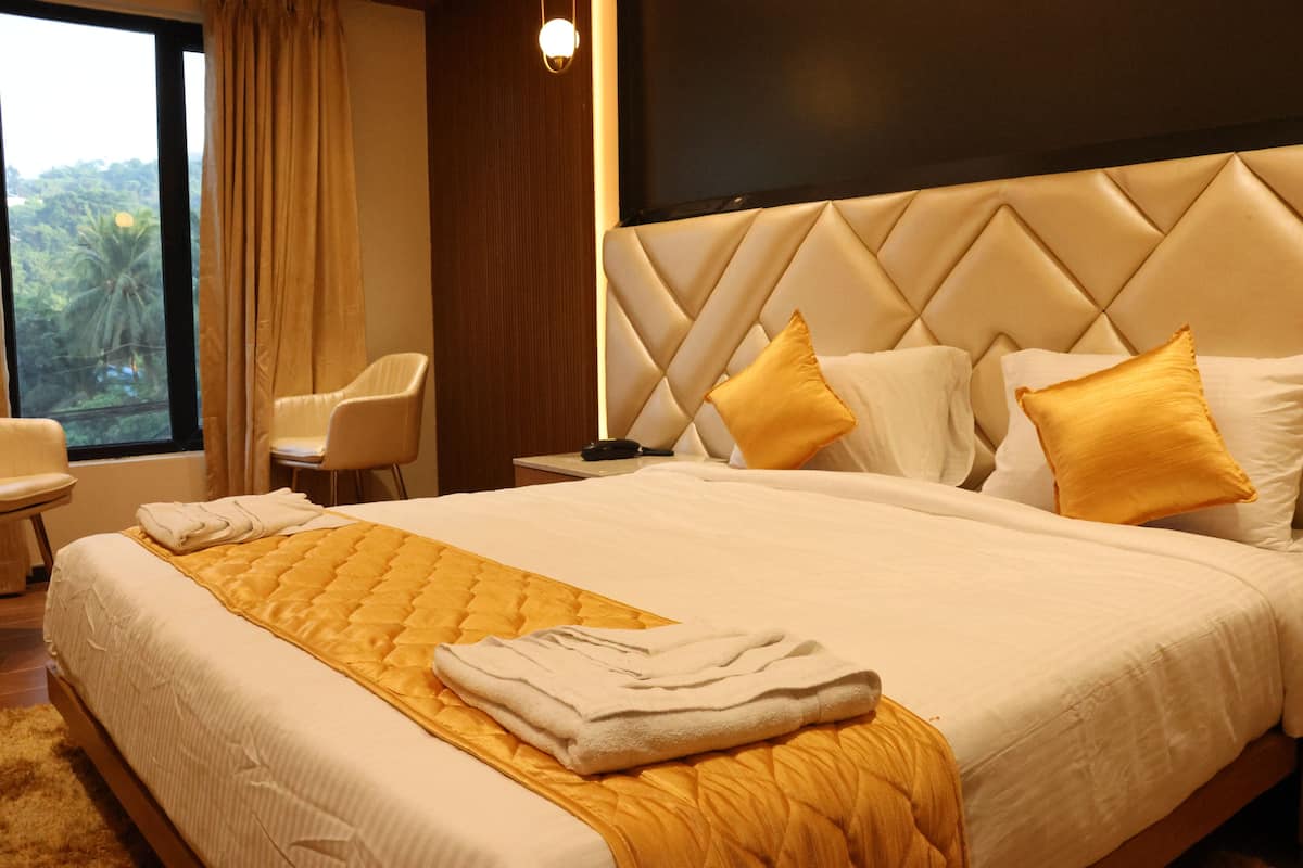 A hotel room with a large bed, a nightstand, a chair, and a view of the outdoors.
