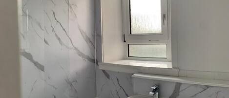 A bathroom with a bathtub, a sink, and a window above the mirror.