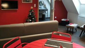 Een moderne woonkamer met een rode bank, een rode eettafel en een kerstboom.