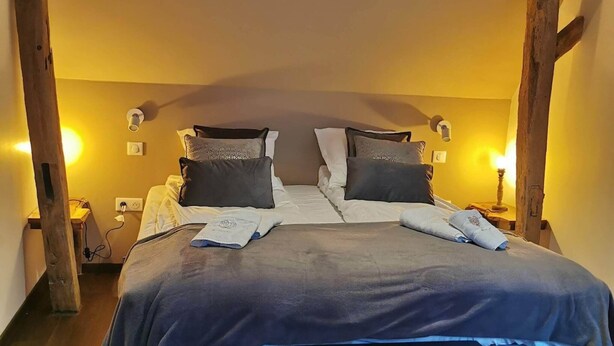 Een slaapkamer met een groot bed, houten balken en twee bedlampjes.
