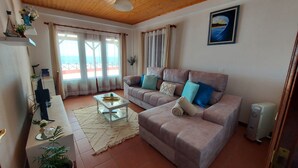 A living room with a sofa, a coffee table, and a radiator. - Maiata Beach House 1 (Machico)