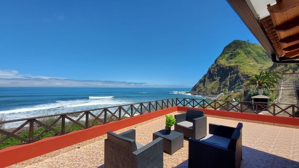 A balcony with outdoor seating overlooking a coastal view. - Maiata Beach House 1 (Machico)