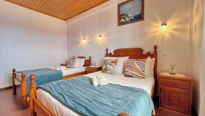 A hotel room with two wooden beds, a painting on the wall, and wall-mounted lights. - Maiata Beach House 1 (Machico)