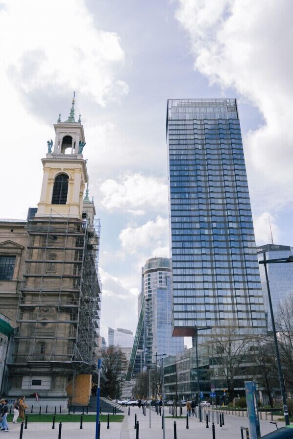 A historic building with a clock tower and modern glass skyscraper in the background.