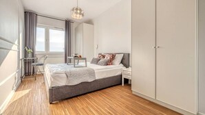 Ein modernes Schlafzimmer mit Bett, Nachttisch und Kleiderschrank.