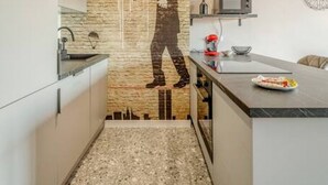 Eine schmale Küche mit Steinrückwand, einer Edelstahl-Dunstabzugshaube und einer Arbeitsplatte aus Granit.