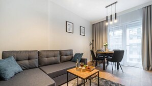 A modern living room with a grey sectional sofa, a wooden coffee table, and a dining area with a table and chairs.