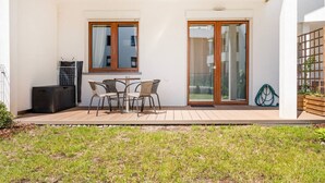 A patio with a table and chairs, a heater, and a window with curtains.