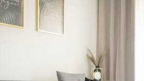A minimalist living room with a grey sofa, a small white table, and a vase with dried plants.