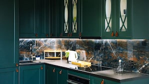 A kitchen with dark green cabinets, a marble backsplash, and a sink. - Warsaw Studio Apartment - City View, Parks nearby by Rentujemy (Warszawa)
