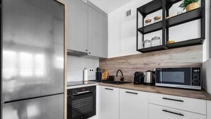 Una cucina moderna con elettrodomestici in acciaio inossidabile, mobili bianchi e un piano di lavoro in legno.