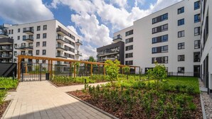 Un complexe d’appartements moderne composé de plusieurs immeubles, doté d’un jardin central agrémenté de sentiers et d’une entrée sécurisée.