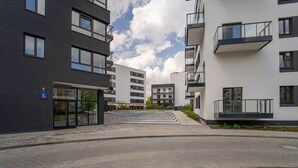 Un immeuble résidentiel moderne, doté de plusieurs étages, de balcons et d’un espace d’entrée pavé.